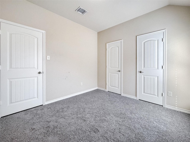 unfurnished bedroom featuring lofted ceiling and dark carpet