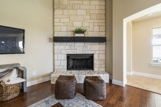 living room with a stone fireplace and hardwood / wood-style floors