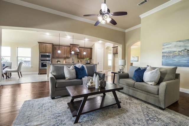 living room featuring hardwood / wood-style flooring, ceiling fan, ornamental molding, and sink