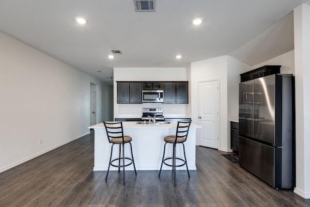 kitchen with a kitchen island with sink, sink, dark wood-type flooring, and stainless steel appliances