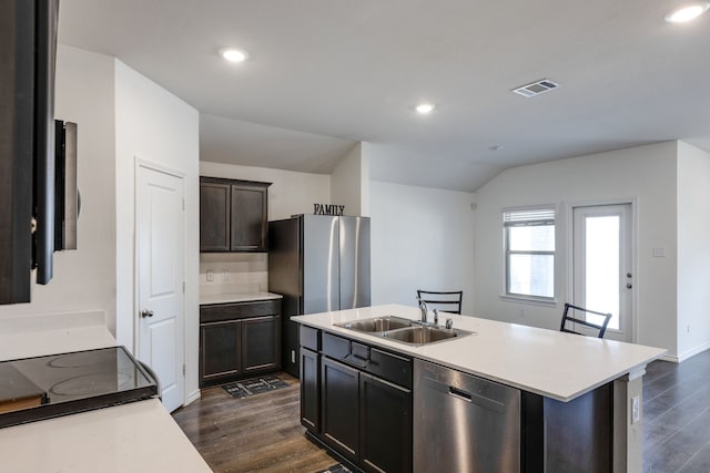 kitchen with sink, a kitchen breakfast bar, dark hardwood / wood-style flooring, an island with sink, and stainless steel appliances