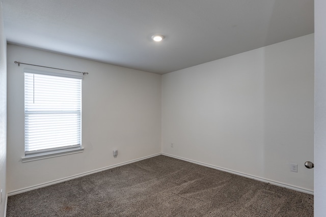 spare room featuring dark colored carpet