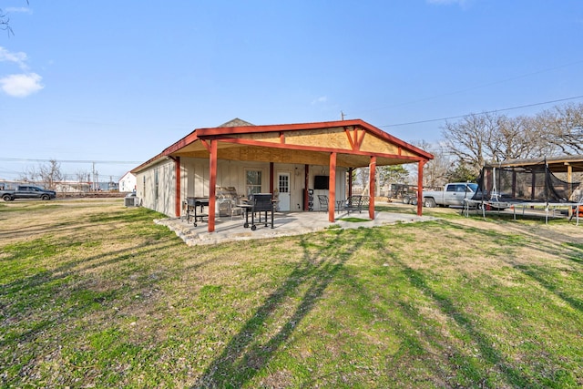 rear view of house featuring a lawn, a trampoline, and a patio area