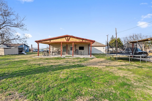 rear view of property with a yard, a patio, and a trampoline