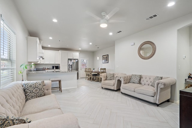 living room with ceiling fan, sink, and light parquet floors