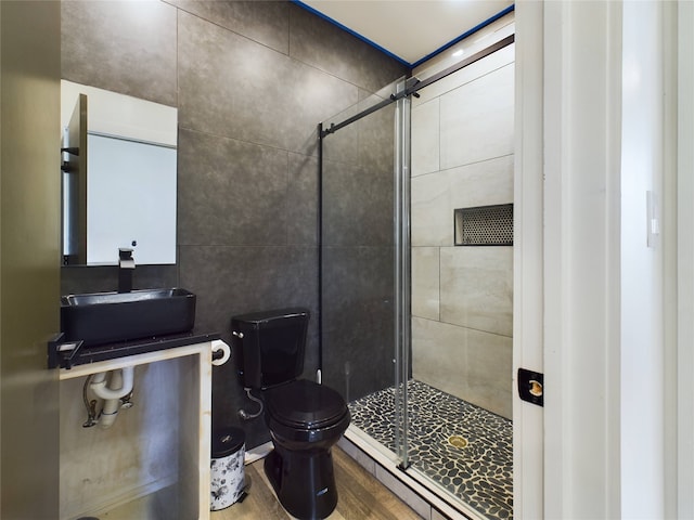 full bath featuring toilet, wood finished floors, a sink, a shower stall, and tile walls