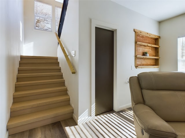 staircase with wood finished floors and baseboards