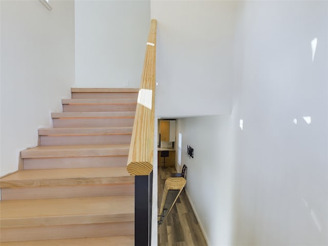 staircase featuring baseboards and wood finished floors