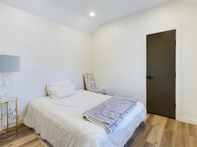 bedroom featuring lofted ceiling, baseboards, wood finished floors, and recessed lighting