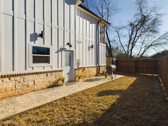 view of property exterior with a fenced backyard, board and batten siding, and a patio