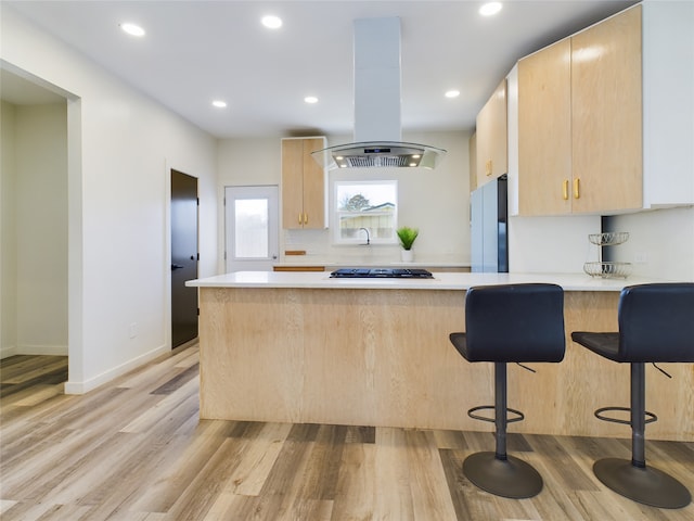 kitchen with light countertops, light brown cabinets, freestanding refrigerator, and island range hood