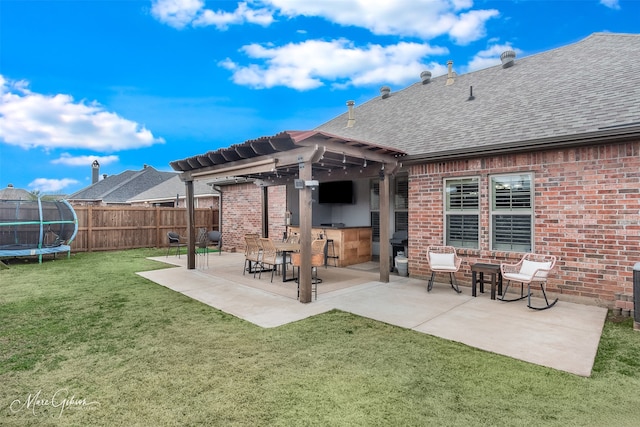 rear view of house featuring exterior bar, a lawn, a trampoline, and a patio area