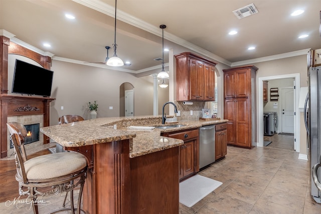 kitchen with a breakfast bar, sink, hanging light fixtures, appliances with stainless steel finishes, and a fireplace