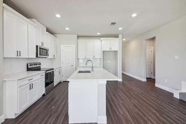 kitchen with white cabinetry, sink, stainless steel appliances, and an island with sink