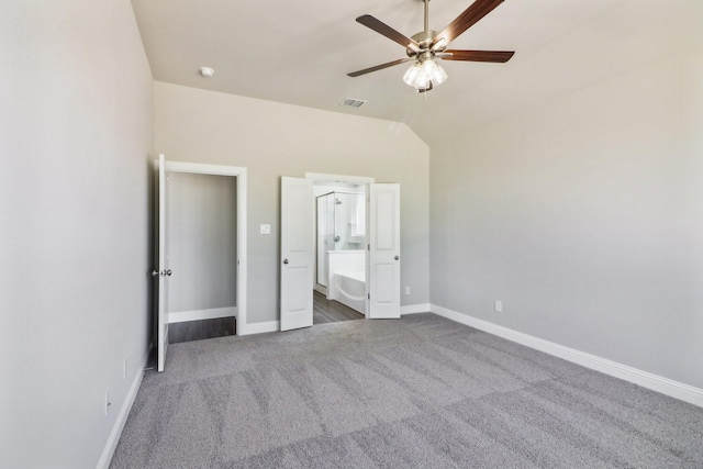 unfurnished bedroom featuring a walk in closet, dark colored carpet, vaulted ceiling, and ceiling fan