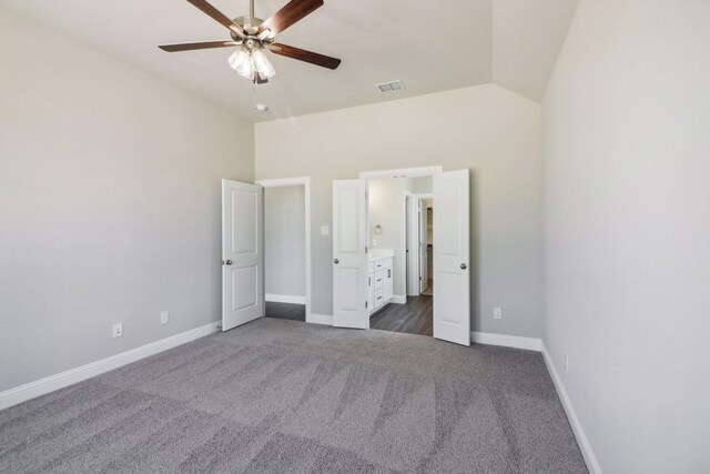 unfurnished bedroom featuring ceiling fan, ensuite bath, lofted ceiling, and dark carpet