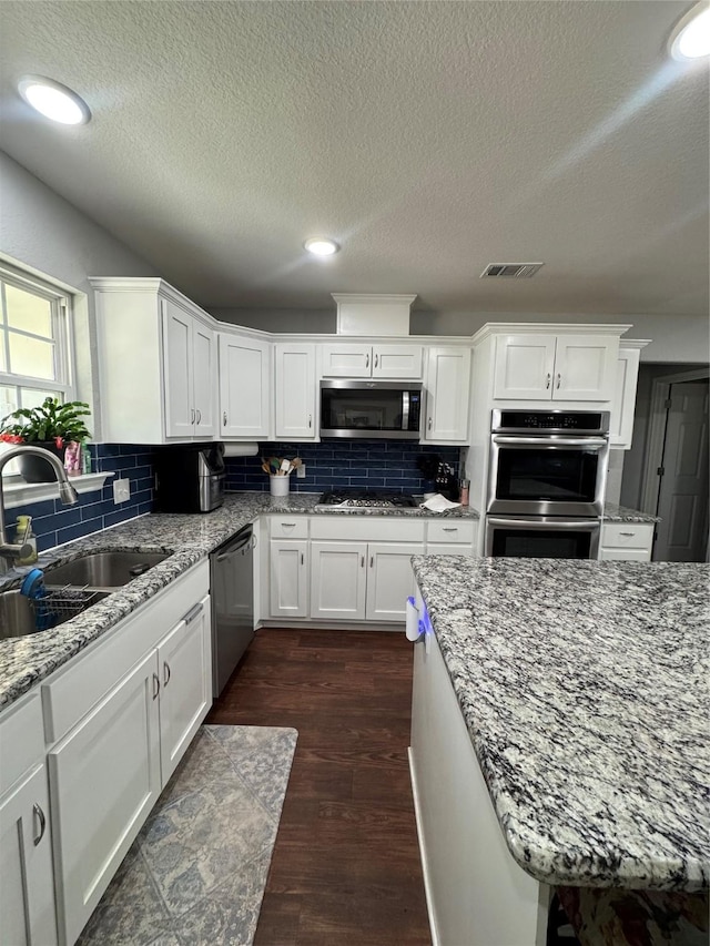 1006 High Point Dr, Mineral Wells, TX 76067 - kitchen with stainless steel appliances, a sink, decorative backsplash, white cabinetry, and a textured ceiling