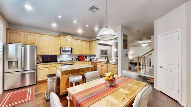 kitchen with a kitchen island, backsplash, hanging light fixtures, stainless steel appliances, and dark wood-type flooring