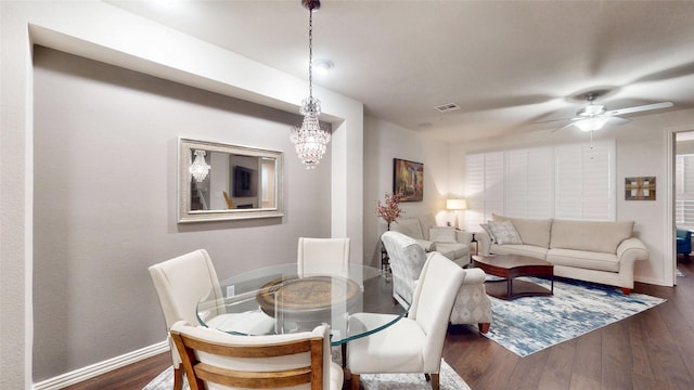 dining room with dark hardwood / wood-style floors and ceiling fan with notable chandelier