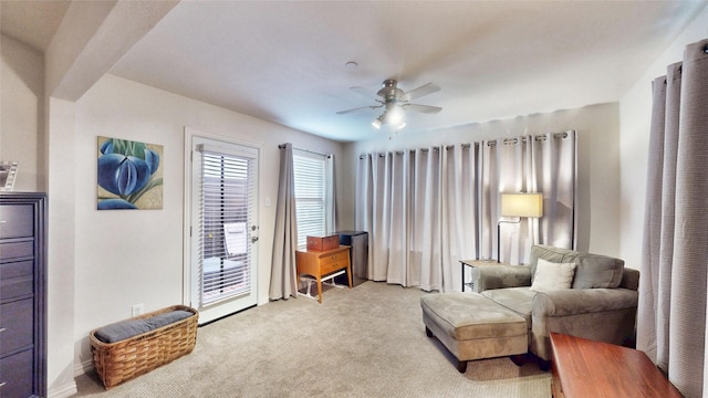 living area with light carpet and ceiling fan