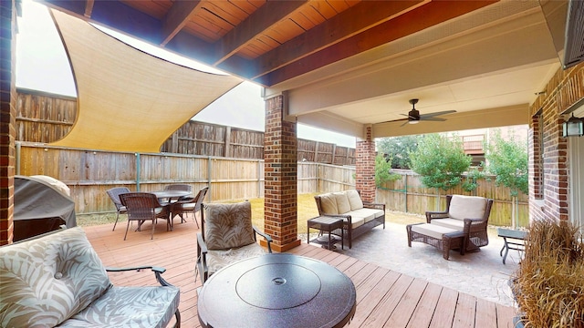 wooden deck with an outdoor living space, grilling area, and ceiling fan