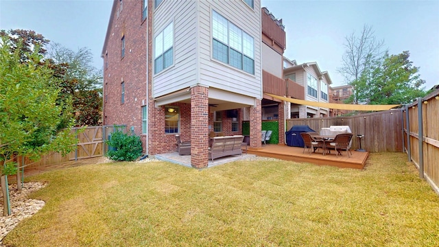 rear view of property featuring an outdoor living space, a wooden deck, a patio area, and a lawn