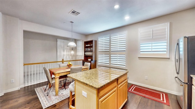 kitchen with dark hardwood / wood-style flooring, pendant lighting, stainless steel fridge, and light stone countertops