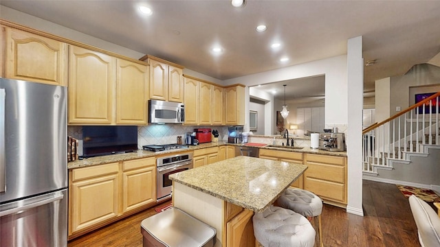 kitchen featuring pendant lighting, sink, stainless steel appliances, a kitchen breakfast bar, and kitchen peninsula