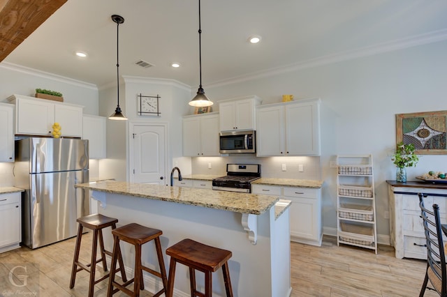 kitchen with stainless steel appliances, light stone countertops, a kitchen island with sink, and white cabinets