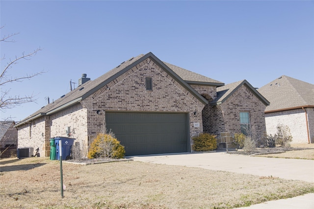 view of front facade with brick siding, a chimney, central air condition unit, concrete driveway, and a garage