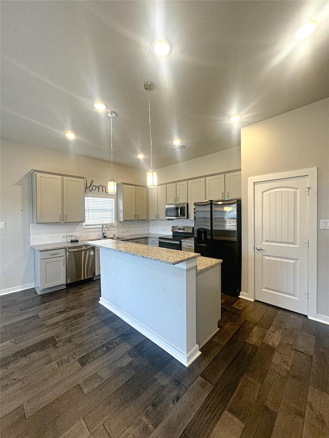 kitchen with light stone counters, pendant lighting, dark wood-style flooring, appliances with stainless steel finishes, and a kitchen island