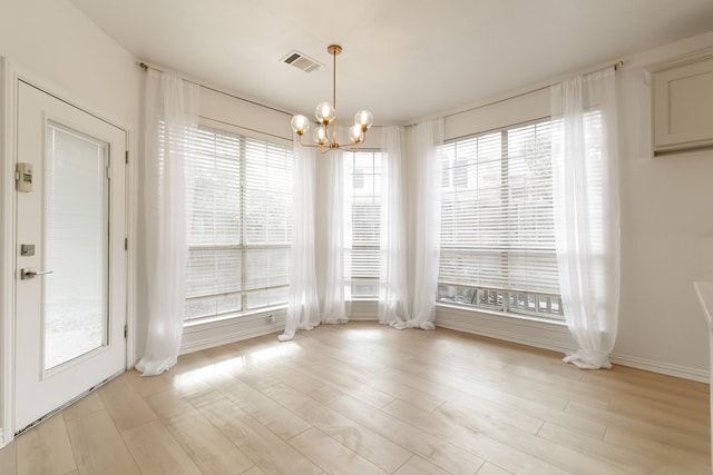 unfurnished dining area with light hardwood / wood-style flooring, a chandelier, and a healthy amount of sunlight