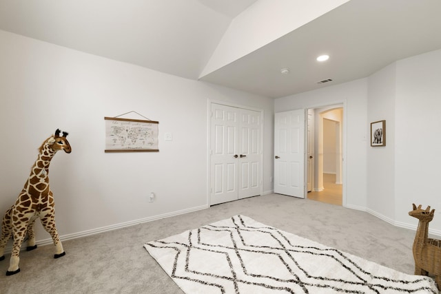 unfurnished bedroom with light colored carpet, lofted ceiling, and a closet