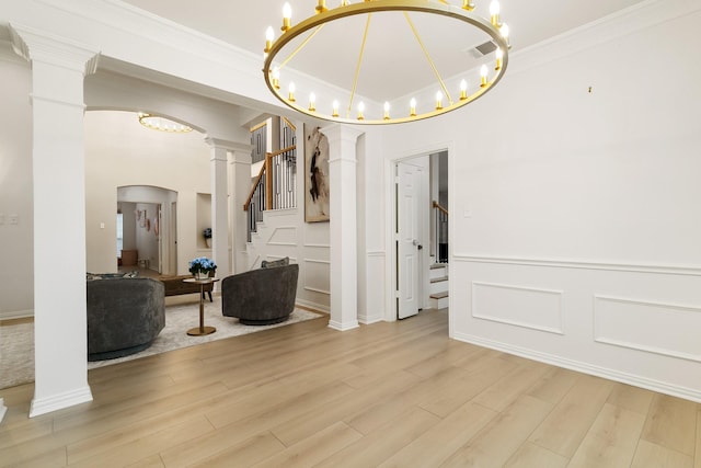 interior space with a notable chandelier, crown molding, light hardwood / wood-style flooring, and ornate columns