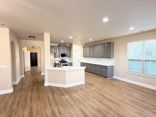 kitchen featuring stainless steel appliances, light hardwood / wood-style flooring, and gray cabinetry