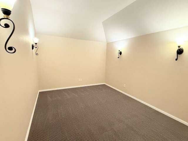 unfurnished room featuring dark carpet and vaulted ceiling