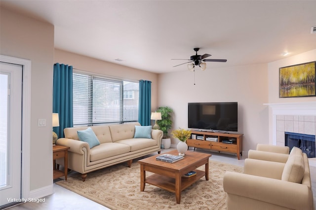 living room with ceiling fan and a tile fireplace