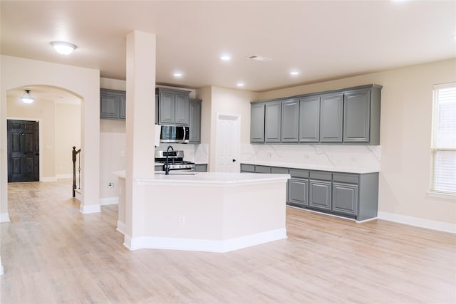 kitchen featuring light hardwood / wood-style flooring, backsplash, gray cabinets, and stainless steel appliances