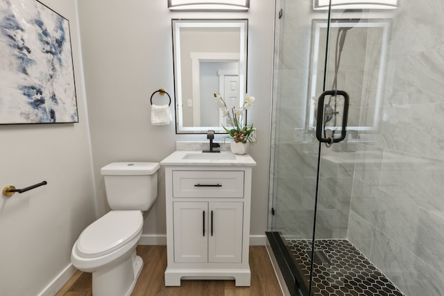 bathroom with hardwood / wood-style flooring, toilet, vanity, and a shower with shower door