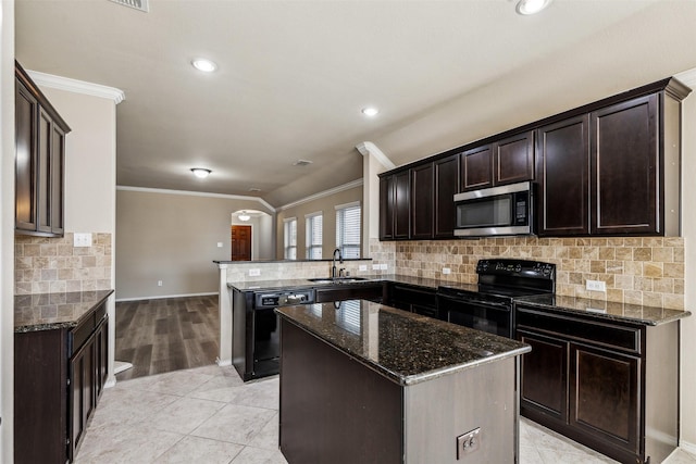 kitchen featuring sink, dark stone countertops, black appliances, a kitchen island, and kitchen peninsula