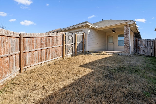 back of property featuring a yard and ceiling fan