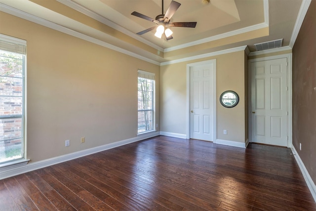 unfurnished bedroom with crown molding, a tray ceiling, and dark hardwood / wood-style flooring