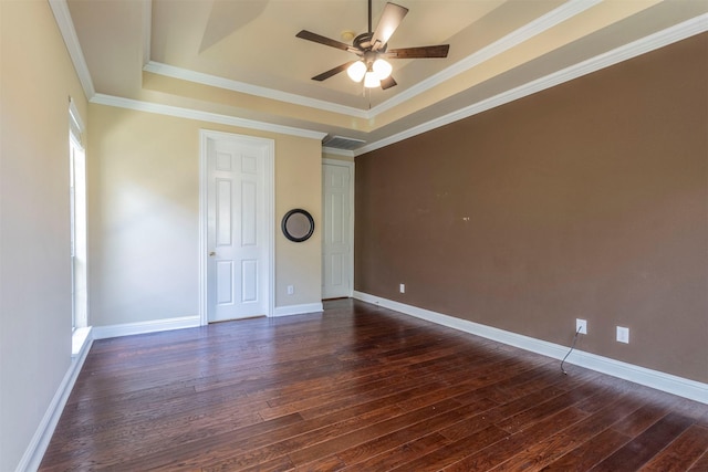 empty room with dark hardwood / wood-style flooring, crown molding, a raised ceiling, and ceiling fan