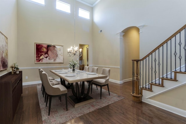 dining area featuring dark hardwood / wood-style flooring, a chandelier, decorative columns, and a high ceiling