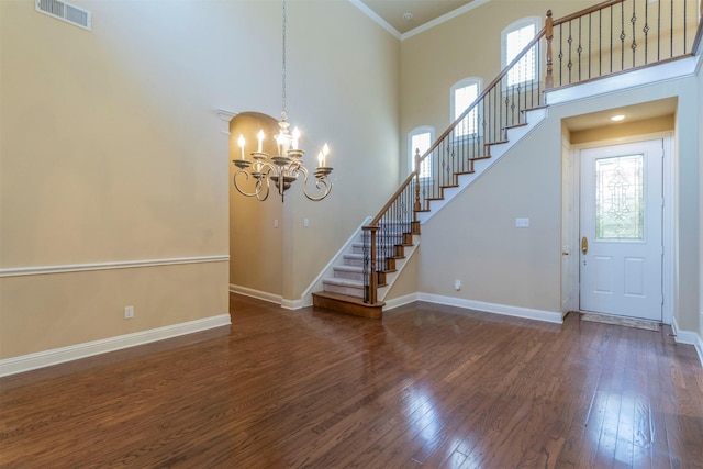 interior space with ornamental molding, dark hardwood / wood-style floors, a chandelier, and a high ceiling