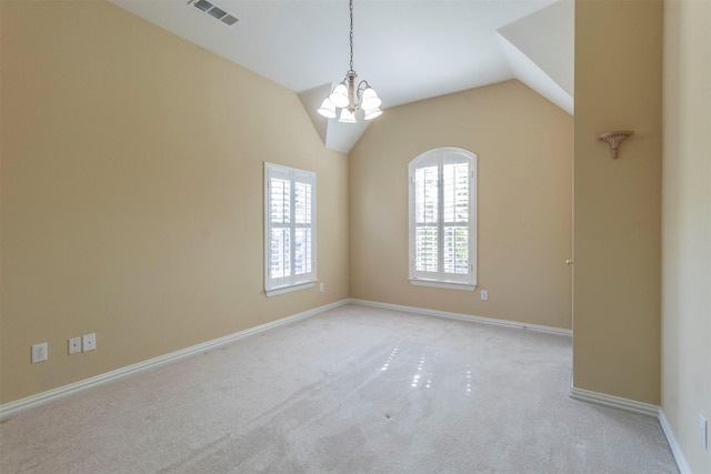 carpeted empty room featuring an inviting chandelier and lofted ceiling