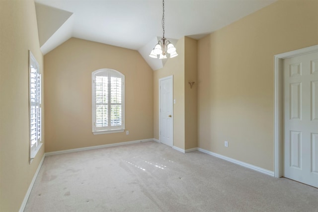 carpeted spare room with vaulted ceiling and a notable chandelier