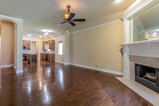 unfurnished living room with vaulted ceiling, a fireplace, ceiling fan, crown molding, and dark wood-type flooring