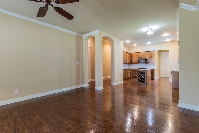 unfurnished living room featuring dark hardwood / wood-style flooring, ornamental molding, and ceiling fan