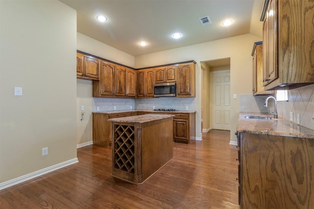 kitchen with a kitchen island, stone countertops, tasteful backsplash, sink, and dark wood-type flooring